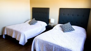 Two single beds with dark headboards, white linens, and patterned pillows. - Amplio departamento, con la mejor ubicación en la ciudad (Chihuahua)