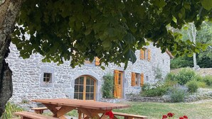 A stone house with a wooden deck and a picnic table. - Large family gîte in Auvergne, 5 bedrooms, linen included, sleeps 12,  (Fayet-Ronaye)