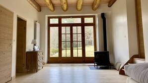 A spacious room with a wooden ceiling, large windows, a fireplace, and a wooden cabinet. - Large family gîte in Auvergne, 5 bedrooms, linen included, sleeps 12,  (Fayet-Ronaye)