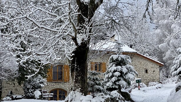 A stone building with a wooden door and windows, surrounded by snow-covered trees and a snow-covered path. - Large family gîte in Auvergne, 5 bedrooms, linen included, sleeps 12,  (Fayet-Ronaye)