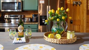 A kitchen with a microwave, stove, refrigerator, and a table with a vase of lemons and a bottle of Tennessee whiskey. - Stop Booking 2 Cabins. This One Sleeps 34. (Pigeon Forge)