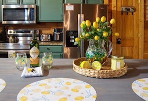 Una cocina con microondas, estufa, refrigerador y un florero con limones en la encimera.