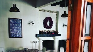 Un coin repas agrémenté d’une cheminée, d’un tableau encadré et d’une guirlande décorative accrochée au mur.