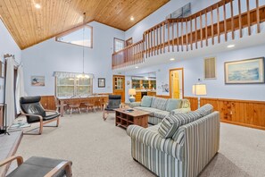 A spacious living area with a high ceiling, a dining table, and a sofa. - 1215 - Corolla Hideaway - Oceanside Corolla Escape w/ Pool & Hot Tub (Corolla)