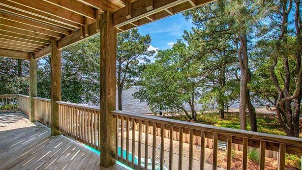 Une terrasse en bois offrant une vue sur un lac et des arbres.