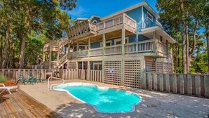 Une maison à deux étages avec une piscine, une terrasse en bois et un jardin clôturé.