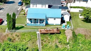 Ein Haus mit blauem Dach, eine hölzerne Anlegestelle, die ins Wasser ragt, und eine Rasenfläche.