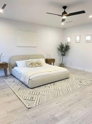 A bedroom with a bed, a ceiling fan, a nightstand, a wall-mounted light, and a potted plant. - Luxury 5 BR home w/ pool perfect for a getaway. (Langley)