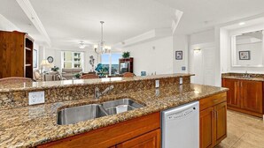Eine moderne Küche mit Granitabdeckungen, Spülbecken aus Edelstahl und Holzschränken.