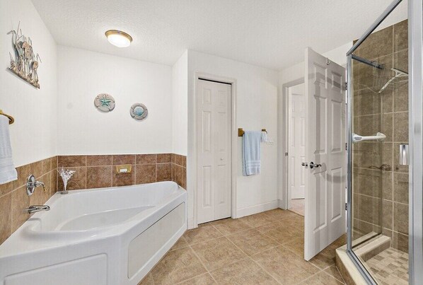 Un baño con bañera, ducha y puerta que da a otra habitación.