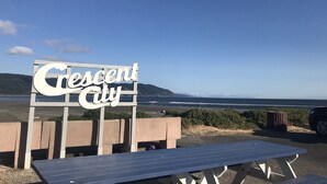 Señal que dice 'Crescent City', con vista al océano y colinas al fondo.