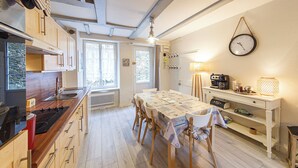 Een kleine keuken met een eethoek, met een fornuis, spoelbak en een gedekte tafel.