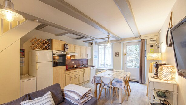 Een compacte keuken met een eethoek, houten kastjes en een inbouwoven.