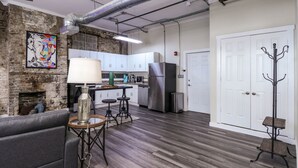A modern kitchen with white cabinets, stainless steel appliances, and a brick wall. - Chic Suite in Central Longview King Bed (Longview)