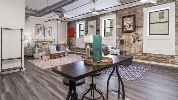 A modern living room with a large table, seating area, and exposed brick walls. - Chic Suite in Central Longview King Bed (Longview)
