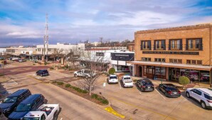 A parking lot with several cars and a building with a sign that reads "S.H. KRESS & CO. 5-10-28 STORE". - Chic Suite in Central Longview King Bed (Longview)