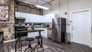 A modern kitchen with white cabinets, stainless steel appliances, and a brick accent wall. - Chic Suite in Central Longview King Bed (Longview)