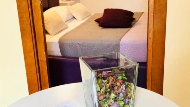 A bedroom with a bed, pillows, and a glass container on a table. - Teatro Massimo Apartament self check-in (Palermo)