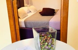 A bedroom with a bed, pillows, and a glass container on a table. - Teatro Massimo Apartment Self-Check-In (Palermo)