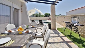 An outdoor patio with a table set for breakfast, a grill, and a pool in the background. - Casa Siesta with swimming pool, jacuzzi & garage (Štrika (Istria))