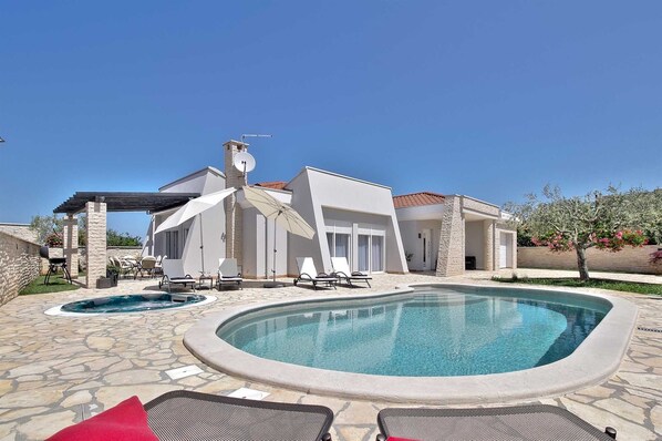 Une maison moderne dotée d’une piscine, de mobilier d’extérieur et d’une pergola.