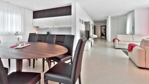 A modern living room with a round dining table, dark leather chairs, a sofa, and a red throw blanket. - Casa Siesta with swimming pool, jacuzzi & garage (Štrika (Istria))
