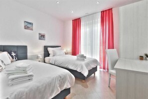 Une chambre d’hôtel moderne équipée de deux lits, d’un bureau et d’une chaise.
