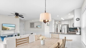 A modern kitchen with white cabinets, stainless steel appliances, and a wooden dining table with chairs.