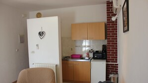 A compact kitchen with wooden cabinets, a microwave, and a small sink.