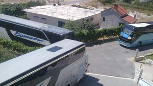 A parking area with a white bus and a blue bus parked.