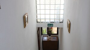 Ein geräumiger Raum mit hoher Decke, einer langen Holzbänklage und einem großen Fenster mit Blick ins Grüne.