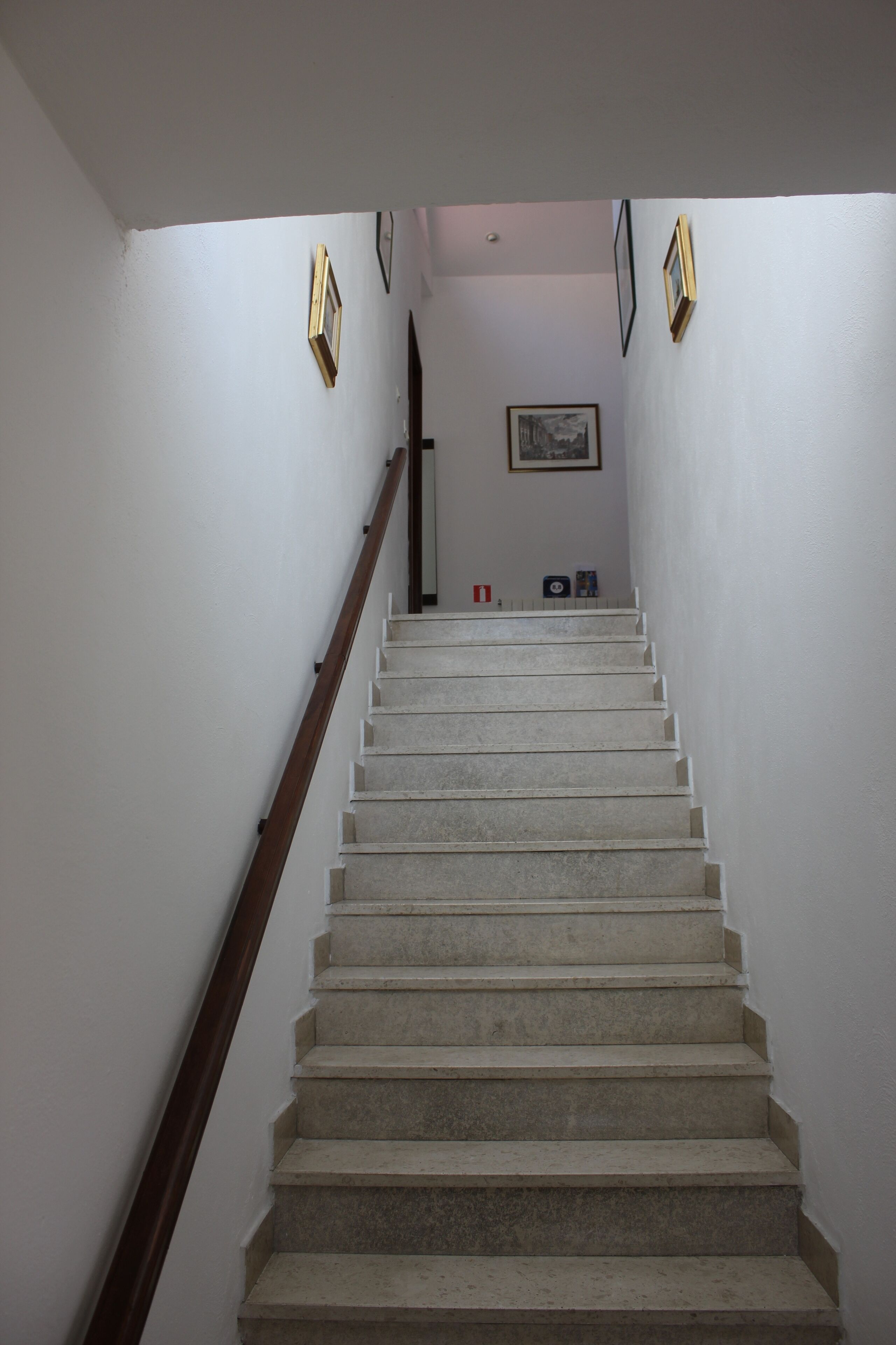 A hallway with a concrete wall, wooden beams, and a framed picture on the wall.
