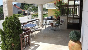 Une terrasse extérieure avec des tables et des chaises, un petit arbre et un vase décoratif.