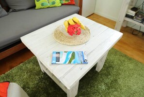 A white coffee table with a woven placemat and a book titled "Cook Islands" on it. - Charming Farm Cottage "Hibiscus" Breakfast & Bikes  (Matavera)