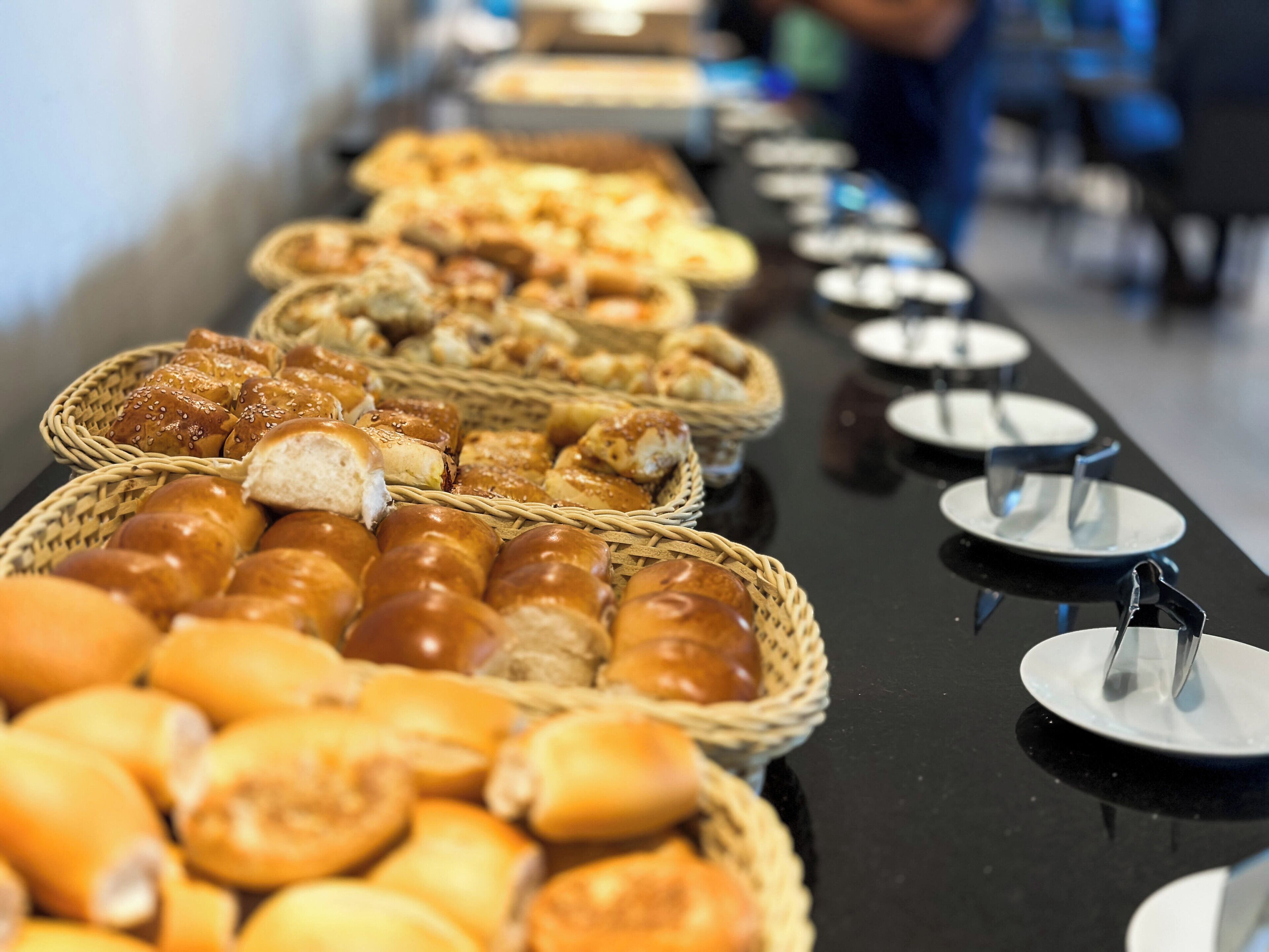 A buffet table with various breads and pastries.