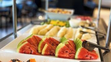 A buffet with various fruits and vegetables, including watermelon slices and papaya chunks.