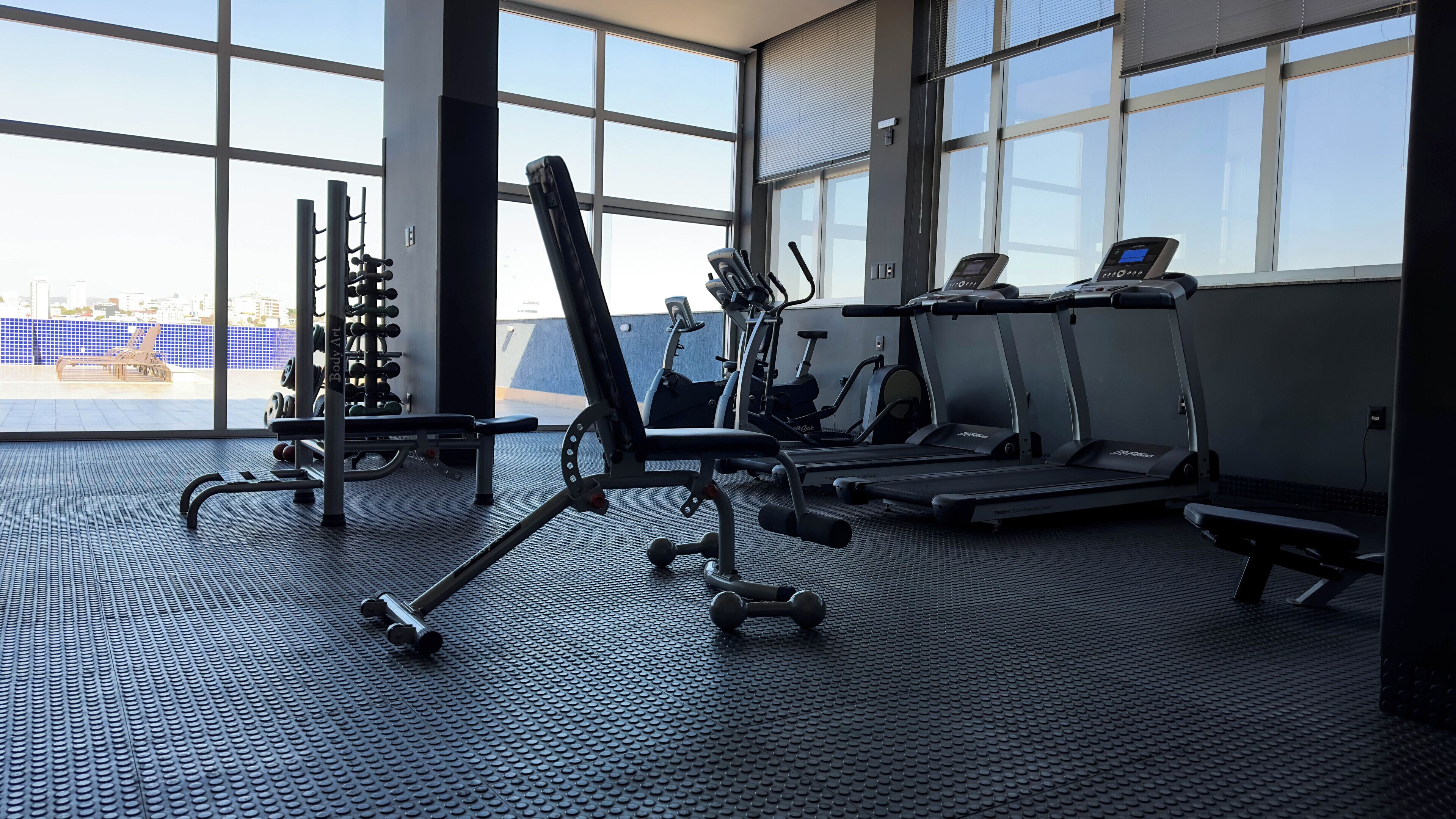 A gym with treadmills, weight machines, and dumbbells.