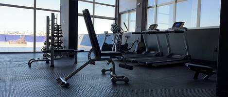 A gym with treadmills, weight machines, and dumbbells.