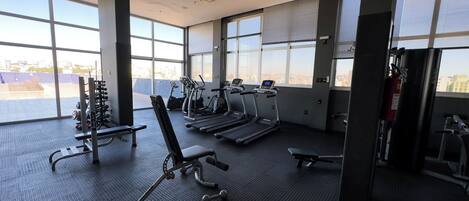 Un gimnasio con cintas de correr, elípticas y máquinas de pesas.