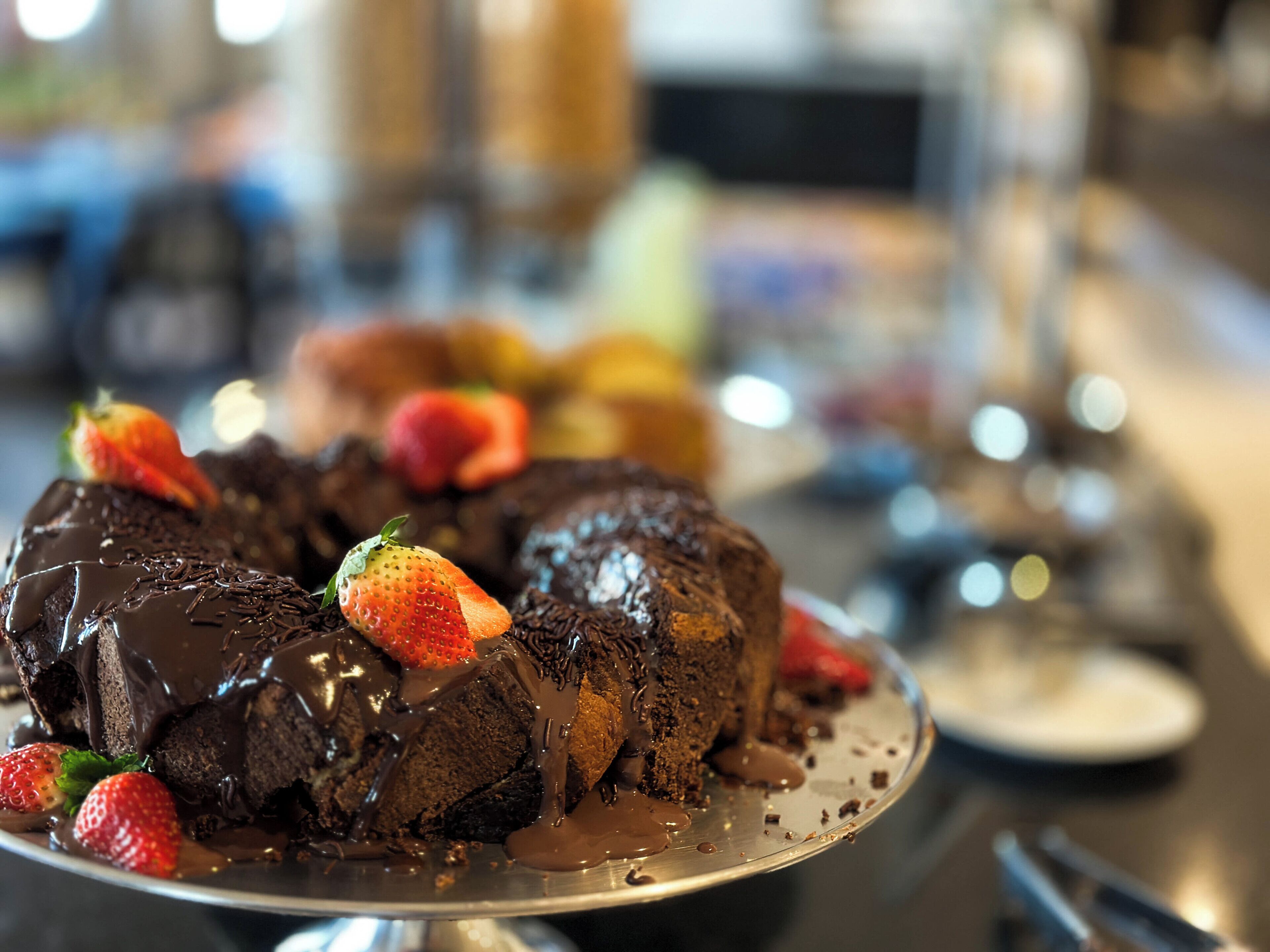 A chocolate dessert with strawberries on a metal serving tray.