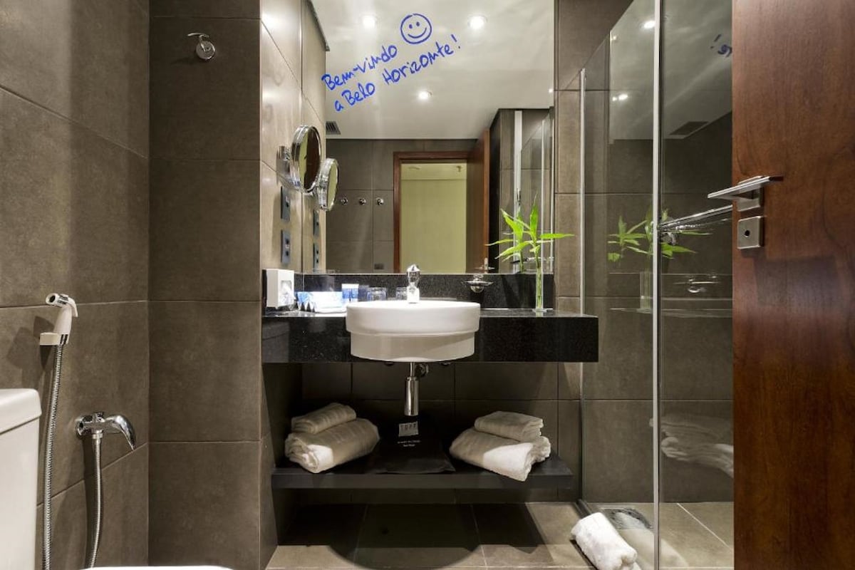 A modern bathroom with a sink, mirror, and towel rack.