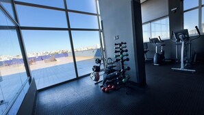 A gym with exercise equipment, large windows, and a view of the city. - Gran Vivenzo Cidade Nova (Belo Horizonte)