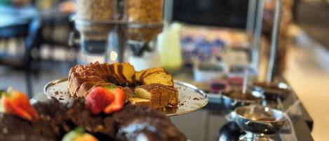 A dessert display with various cakes and pastries, including a chocolate cake with strawberries.