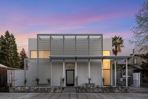 Un edificio moderno de dos plantas con techo plano, ventanas amplias y un área de entrada cubierta.