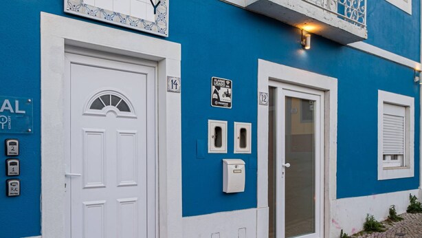 A blue building with white doors and windows, numbered 14 and 12, and a balcony with white railings. - Y.Quebedo - Boutique Apartments - Poetico (Setúbal)