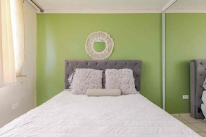 Une chambre à coucher comprenant un lit, une tête de lit, deux oreillers et un élément décoratif fixé au mur.