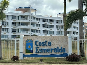Une enseigne pour l’hôtel Costa Esmeralda, avec un bâtiment moderne en arrière-plan.