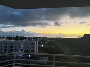 Un quartier résidentiel avec des immeubles, un parking et une vue sur une étendue d’eau au coucher du soleil.