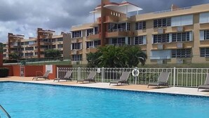 A swimming pool with lounge chairs and a building with multiple balconies in the background. - Apartment with ocean view near Ceiba FerryTerminal (Ceiba)