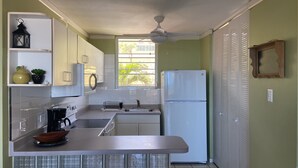 A compact kitchen with white cabinets, a built-in oven, a sink, and a refrigerator. There is a window providing natural light and a ceiling fan. - Apartment with ocean view near Ceiba FerryTerminal (Ceiba)